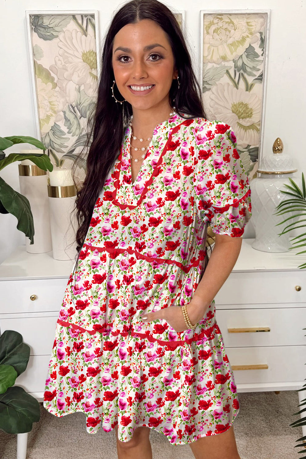 Woman wearing a floral dress in a home setting with decorative elements.