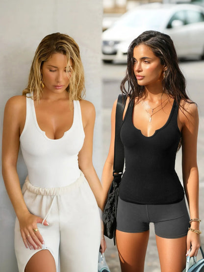 Two women wearing tank tops and shorts outdoors with a car in the background.